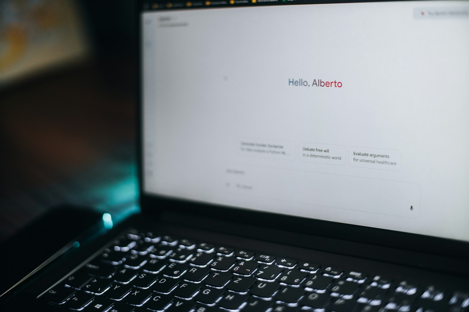 A laptop displays "hello, alberto" on its screen.